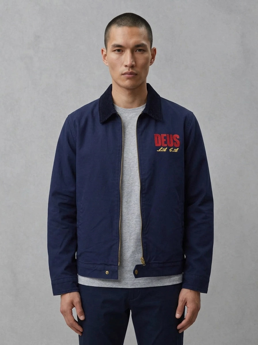 Deus Cutaway veste navy portée de face, col velours côtelé, logo DEUS rouge